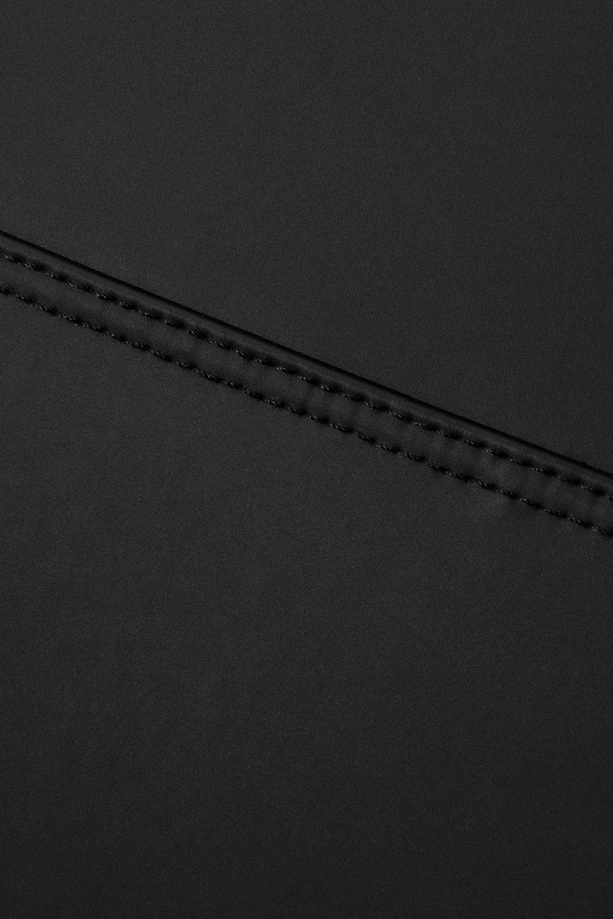 Close-up of a black leather surface with stitching detail